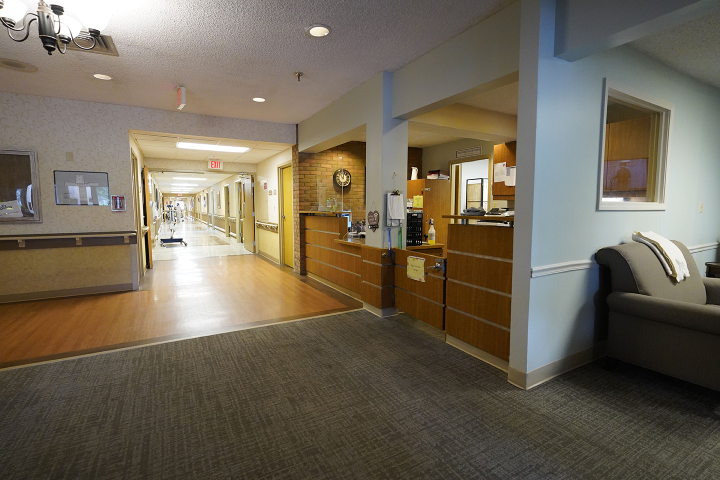 Hallway with exit sign and front desk- Arbors at Carroll